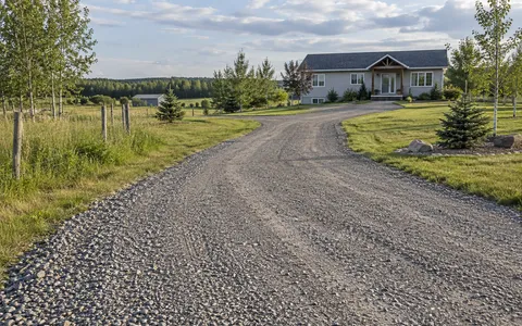 Gravel driveway leading toward a rural farmhouse