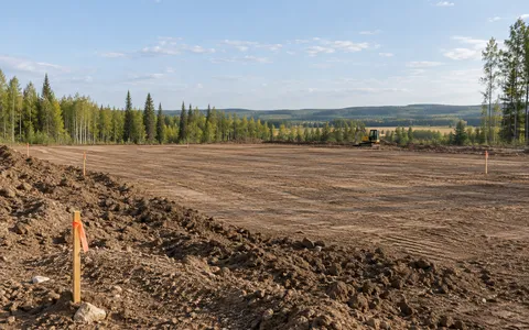 Survey stakes and a cleared earth pad on an acreage
